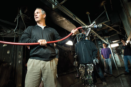 2 Brian Lattimer, vice president of research and development for Jensen Hughes and affiliate professor and principal investigator on Virginia Tech’s robot program, stretches a one-inch hoseline and nozzle to the door of a fire compartment in readiness for it to be used by the robot. Virginia Tech students Mike Rouleau, center, and Jack Newton assisted in the test. 