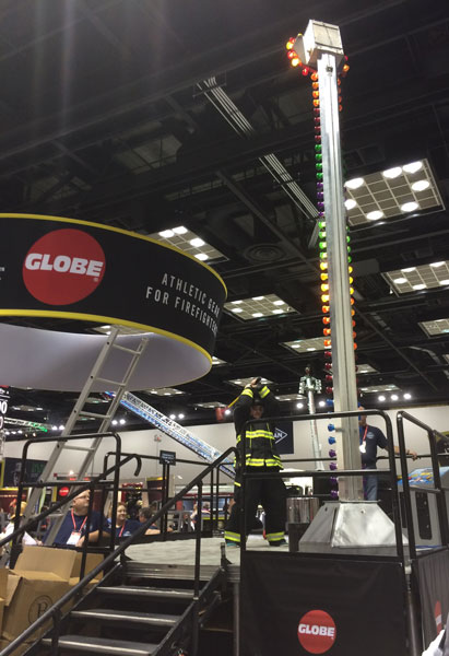 A firefighter participates in the Globe High Striker at the Globe booth at FDIC International 2016.