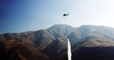 4 A Lockheed Martin K-MAX UAV helicopter drops water on a wildland fire in Boise, Idaho, after a Lockheed Martin Indago quad rotor drone identified hot spots. (Photo courtesy of Lockheed Martin