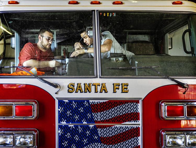 Santa Fe technicians Micheal Olguin, left, and Alex Salazar work Wednesday to switch radios to a new frequency at Fire Station No. 5. (Jim Weber/The New Mexican)